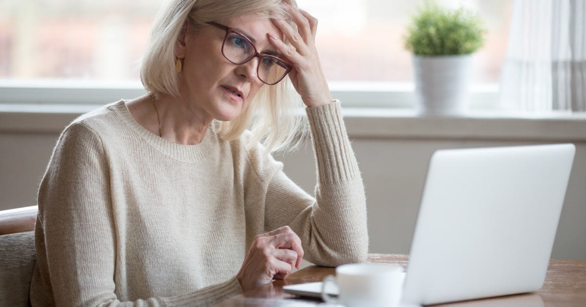 Mujer mayor con gesto preocupado utilizando un portátil para trabajar